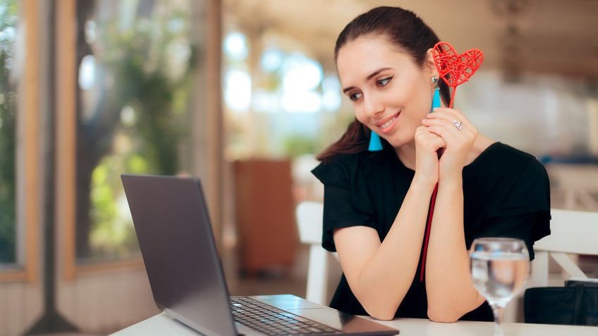 Mulher em casa usando notebook com olhar apaixonado