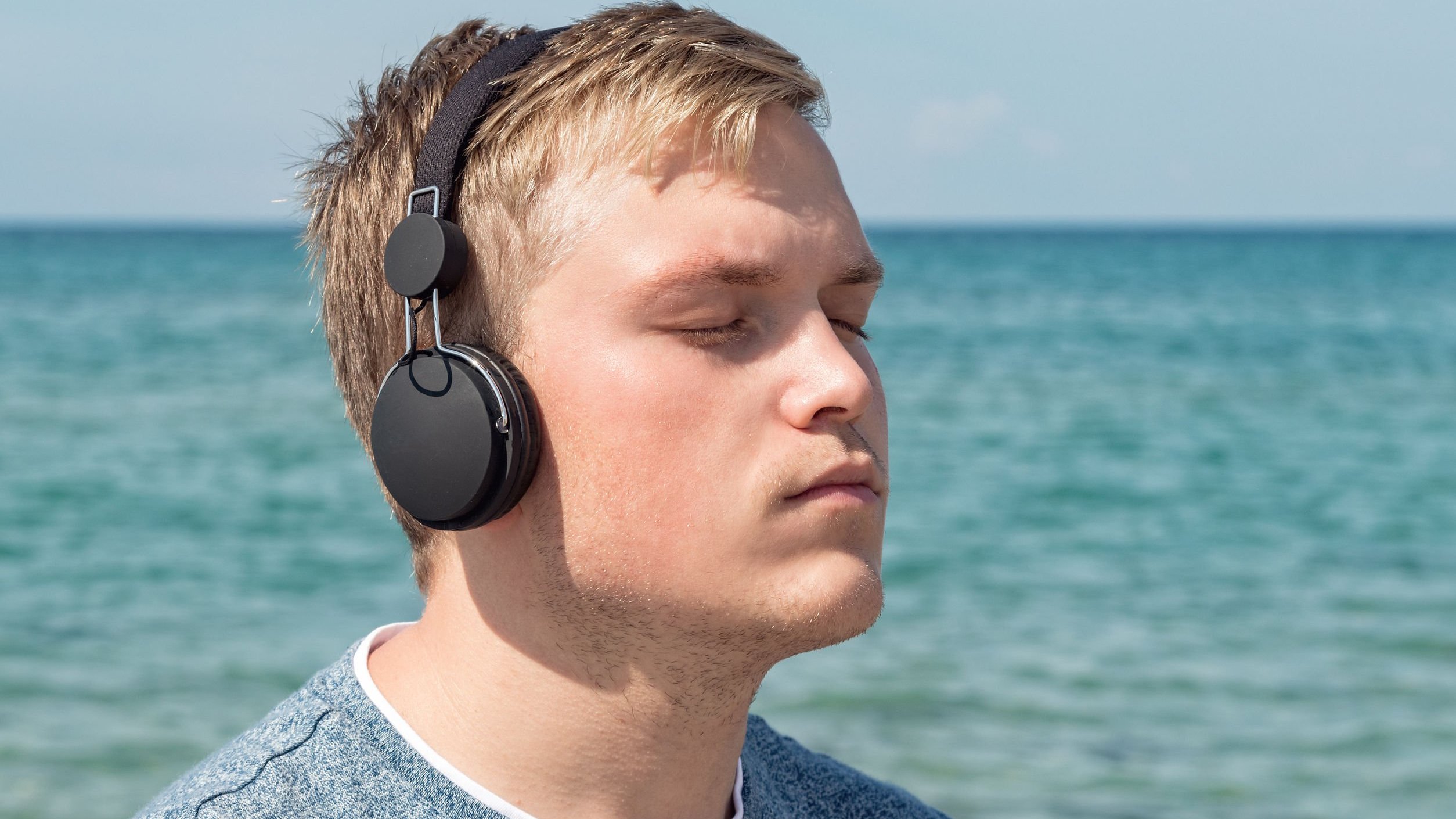 Homem de olhos fechados ouvindo música.