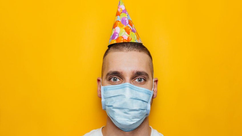 123RF | Yuliia Hurzhos Homem usando chapeuzinho de aniversário e máscara