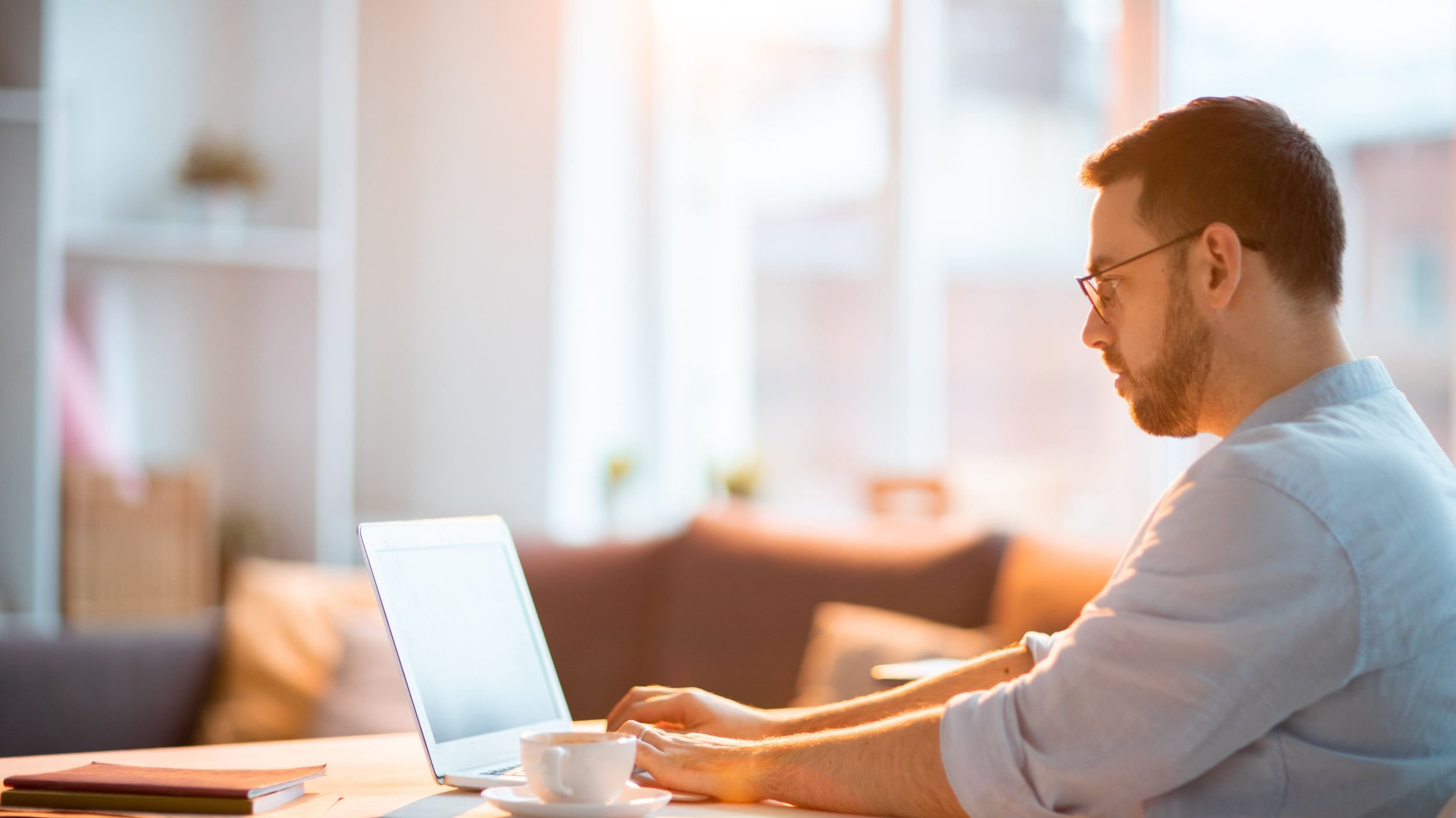 Homem mexendo em notebook, trabalhando em casa.