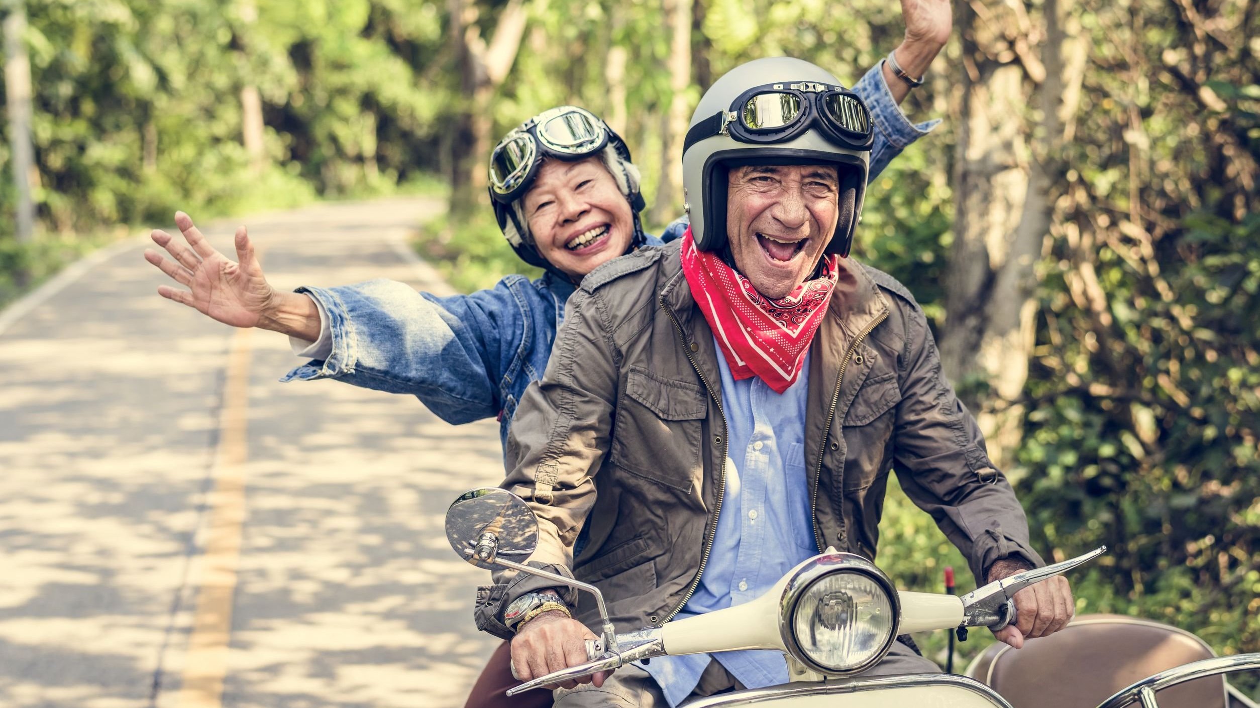 Idosos andando de motocicleta, sorrindo.