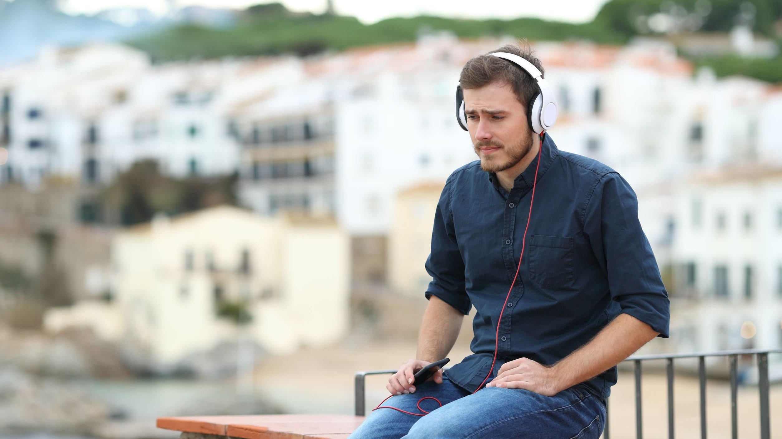 Homem sentado, triste, ouvindo música.