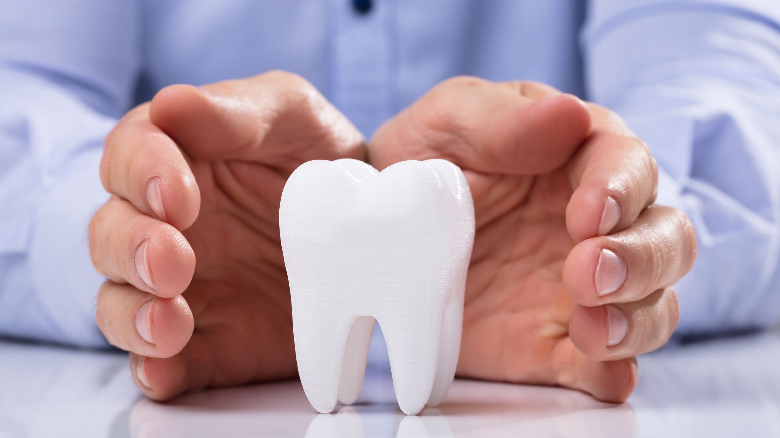 Andriy Popov / 123rf Mãos masculinas brancas ao redor de um dente decorativo.