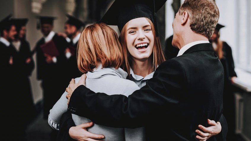 Menina abraçando os pais na formatura