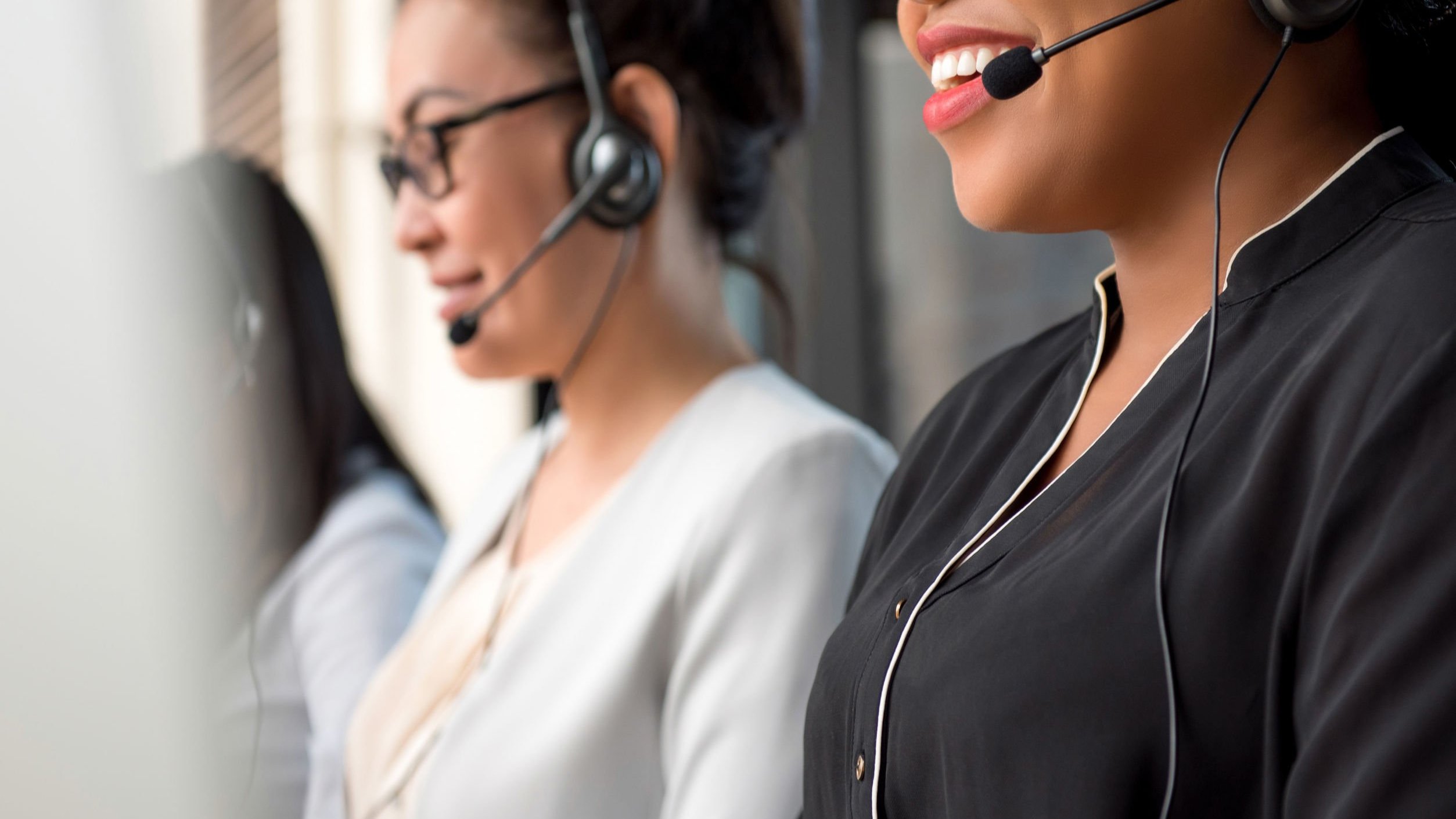 Duas mulheres do telemarketing falando com seus fones