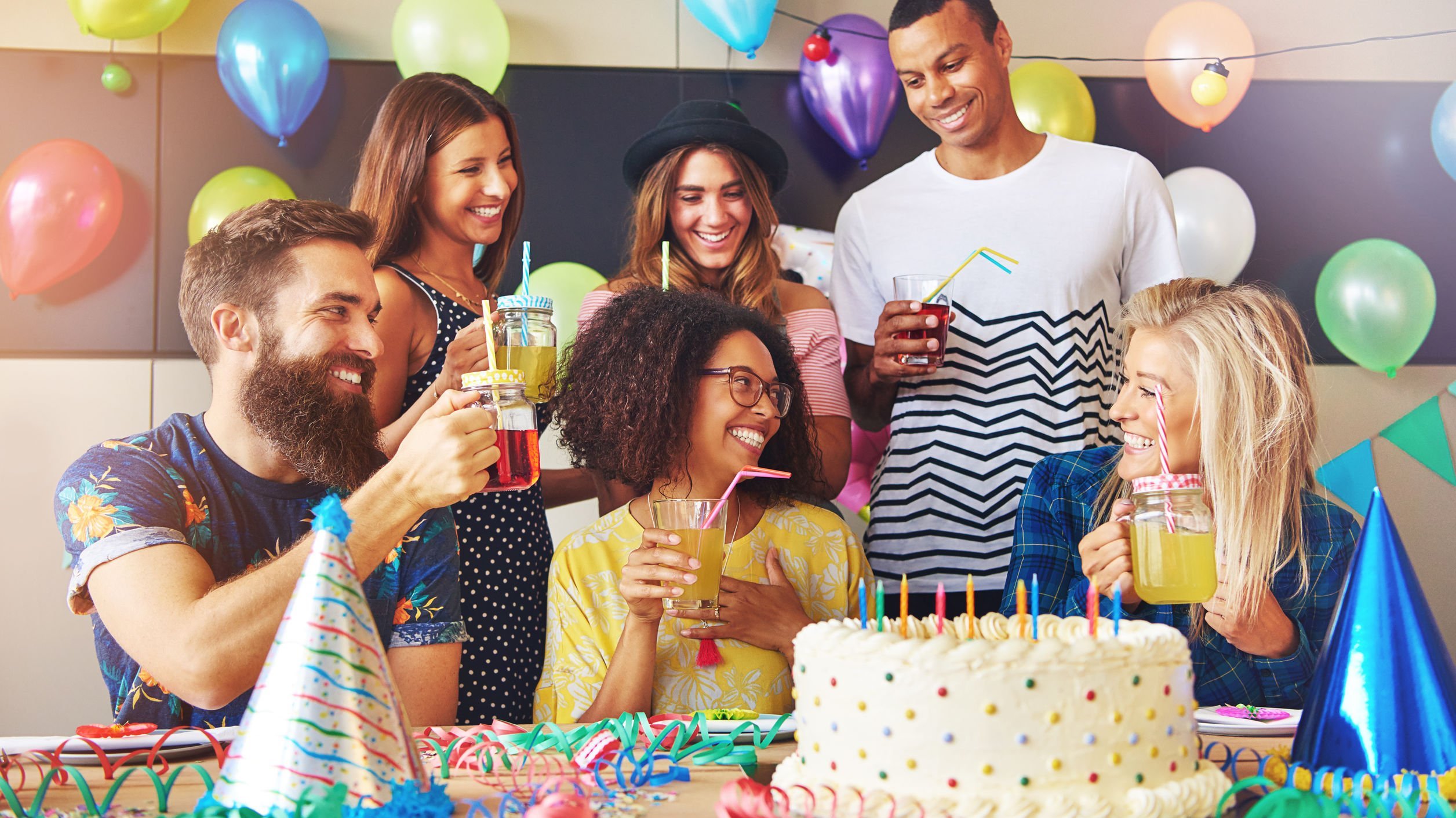 Pessoas reunidas cantando parabéns em torno de bolo de aniversário com velas acesas