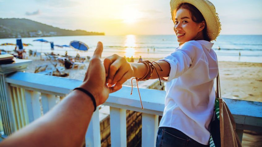 Mulher na praia segurando a mão de amiga