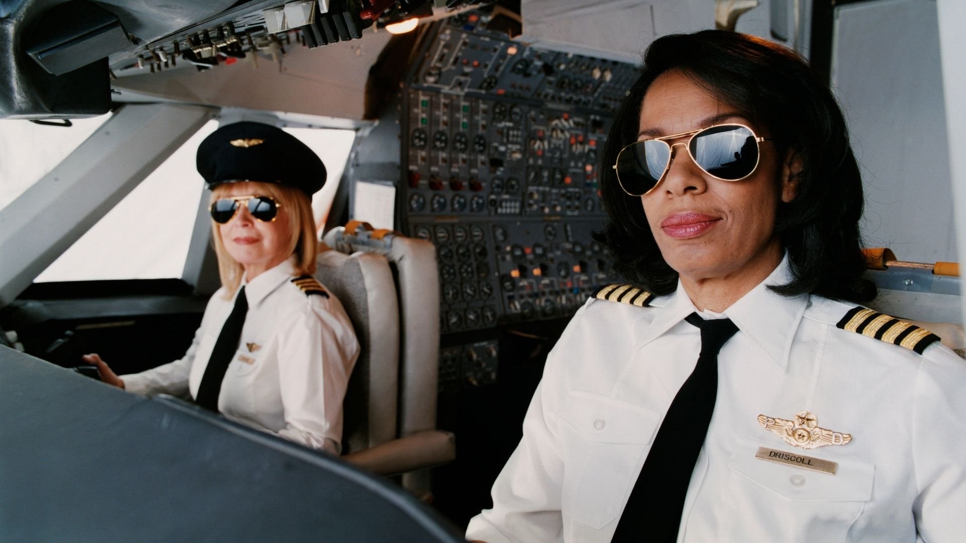 Digital Vision / Getty Images Pro / Canva Duas aviadoras sorrindo na cabine