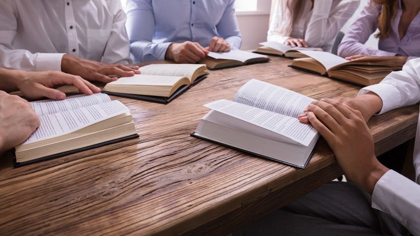 Grupo de pessoas em uma mesa lendo suas Bíblias