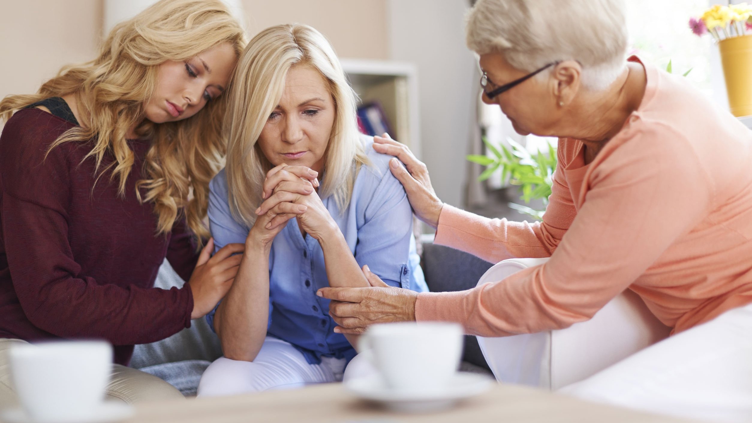 Mulheres brancas e loiras com expressões tristes prestando apoio.