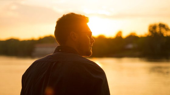 Homem ao lado de um lago e um pôr do sol