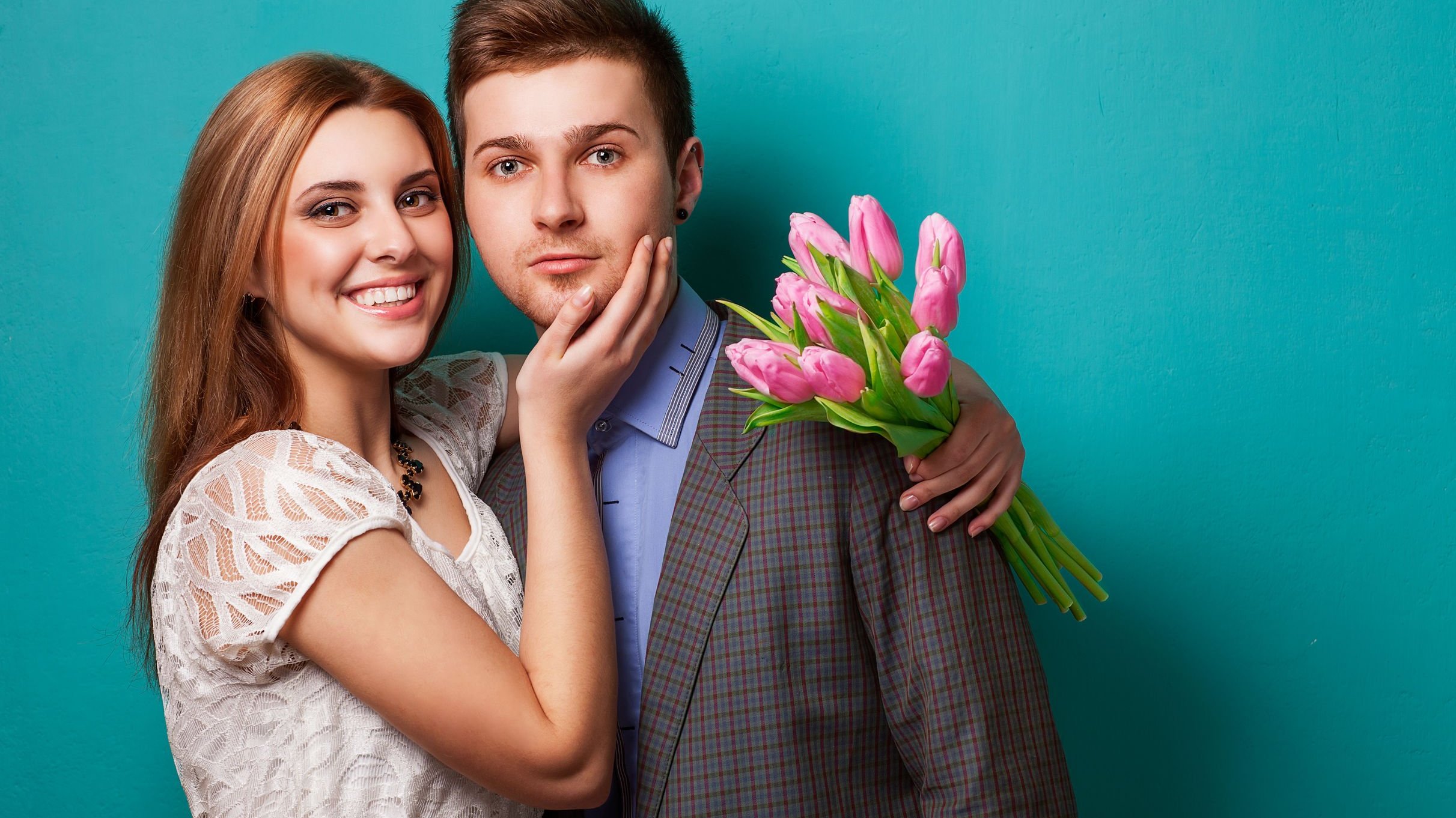 Mulher sorrindo e segurando flores,abraçando homem.