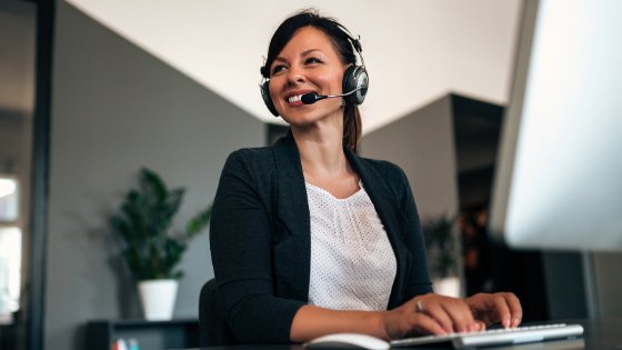 Recepcionista olhando para o lado sorrindo e digitando