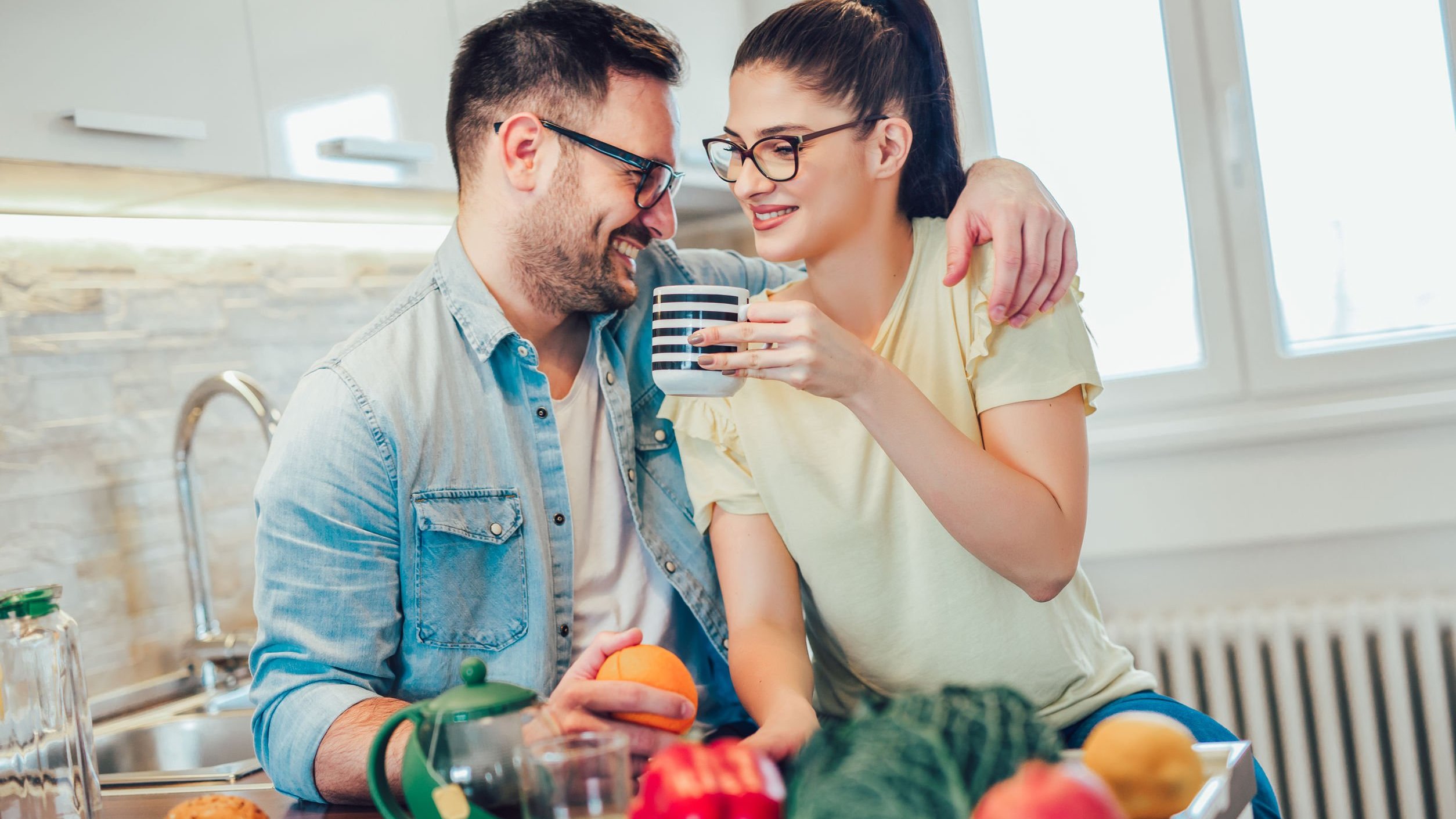 Homem e mulher se abraçando e sorrindo. Tomando café.