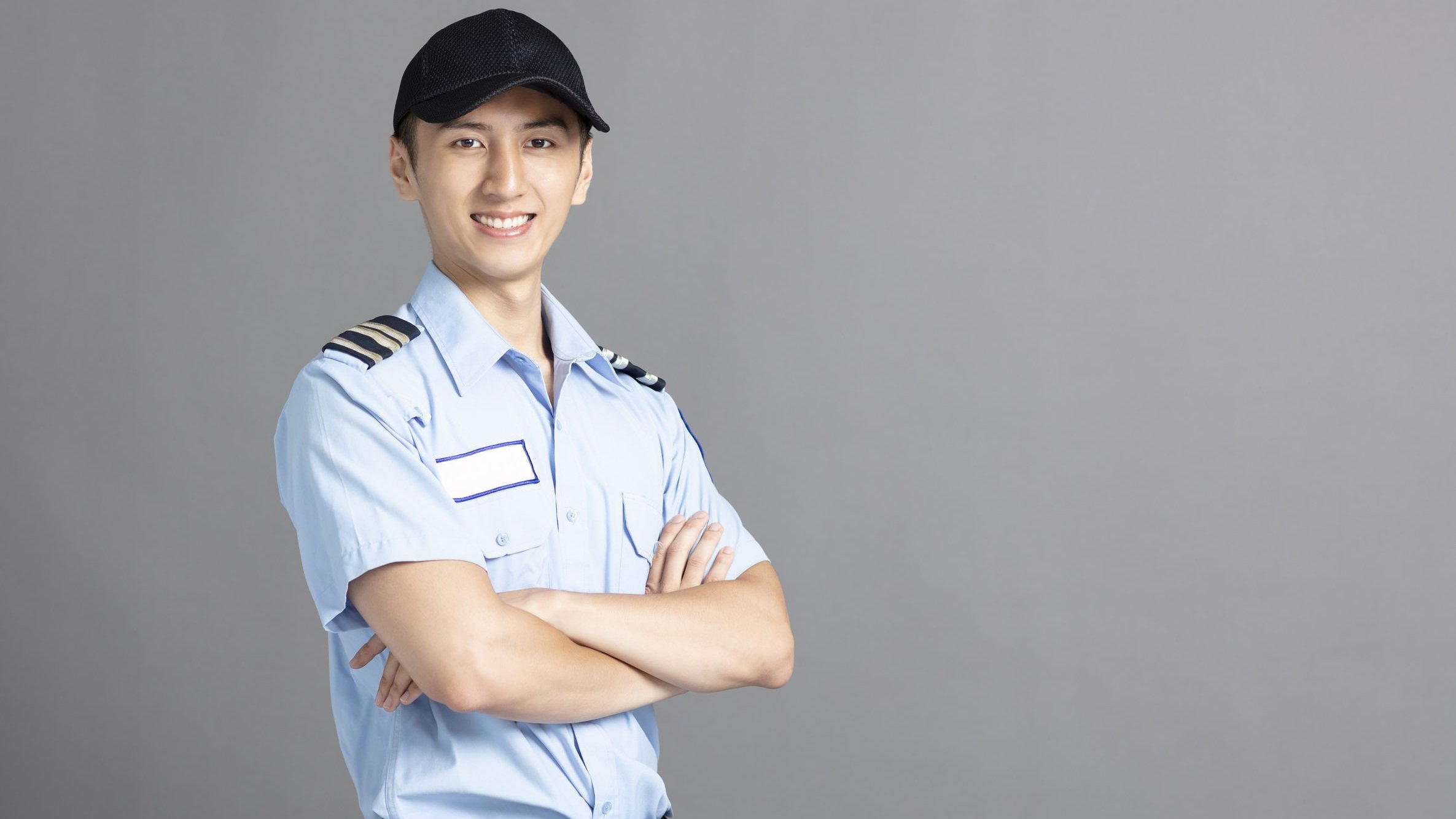 Homem, segurança, sorrindo de braços cruzados usando uniforme.