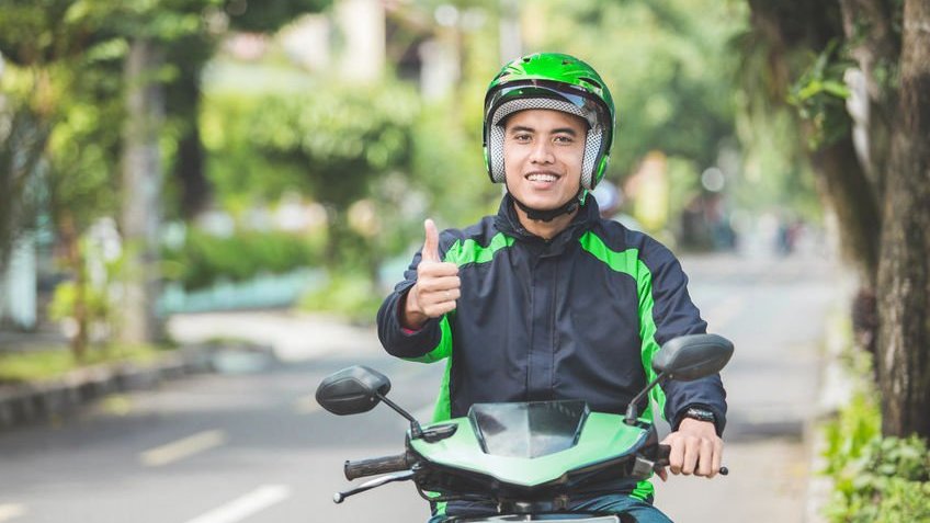 Mototaxista sorrindo e erguendo polegar