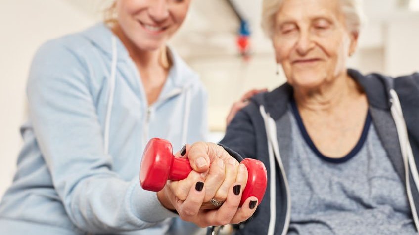 Terapeuta ajudando idosa a fazer exercício