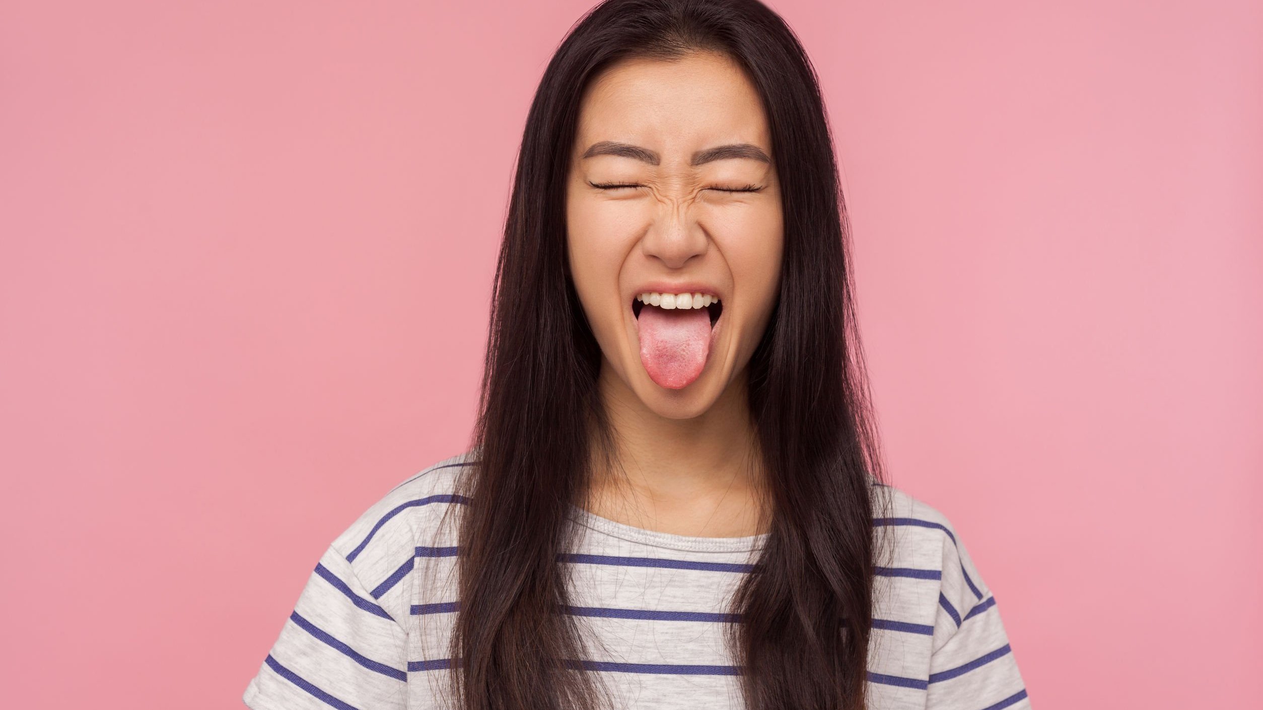 Mulher de olhos fechados mostrando a lingua.