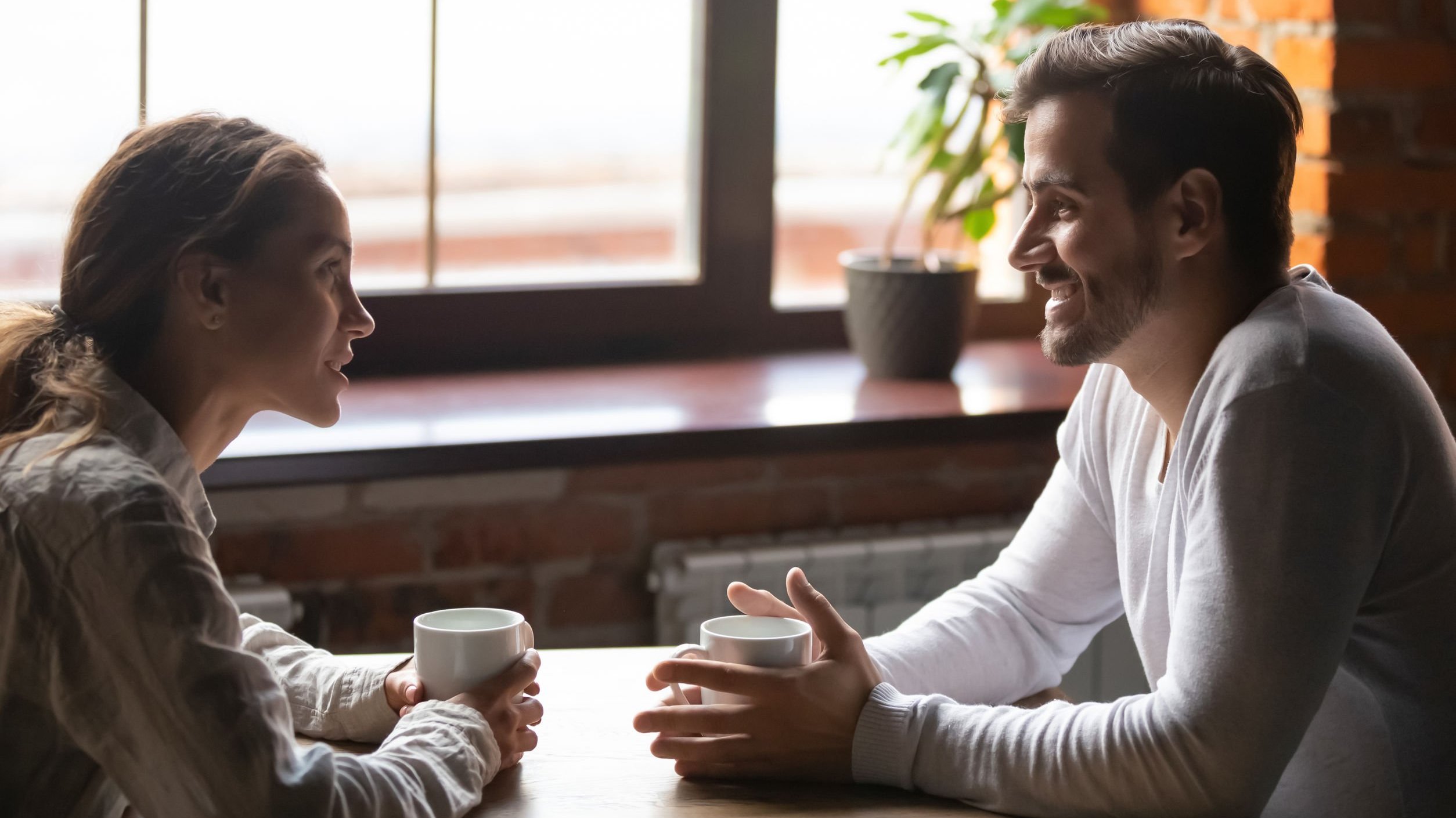 Homem e mulher conversando e sorrindo em um restaurante.