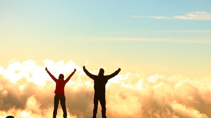 Pessoas de braços erguidos e nuvens ao fundo