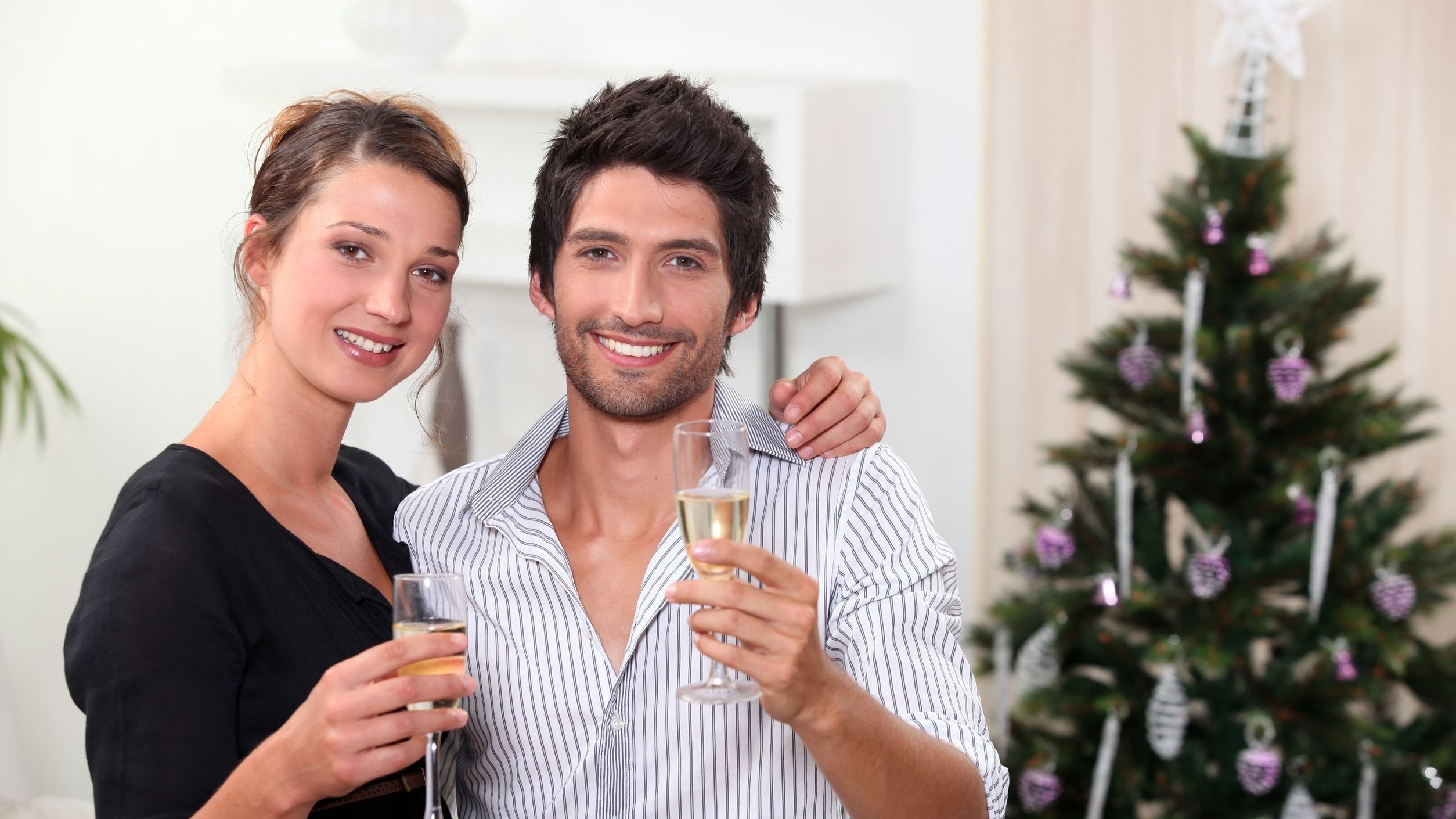 Casal sorrindo e segurando taças de  champanhe.