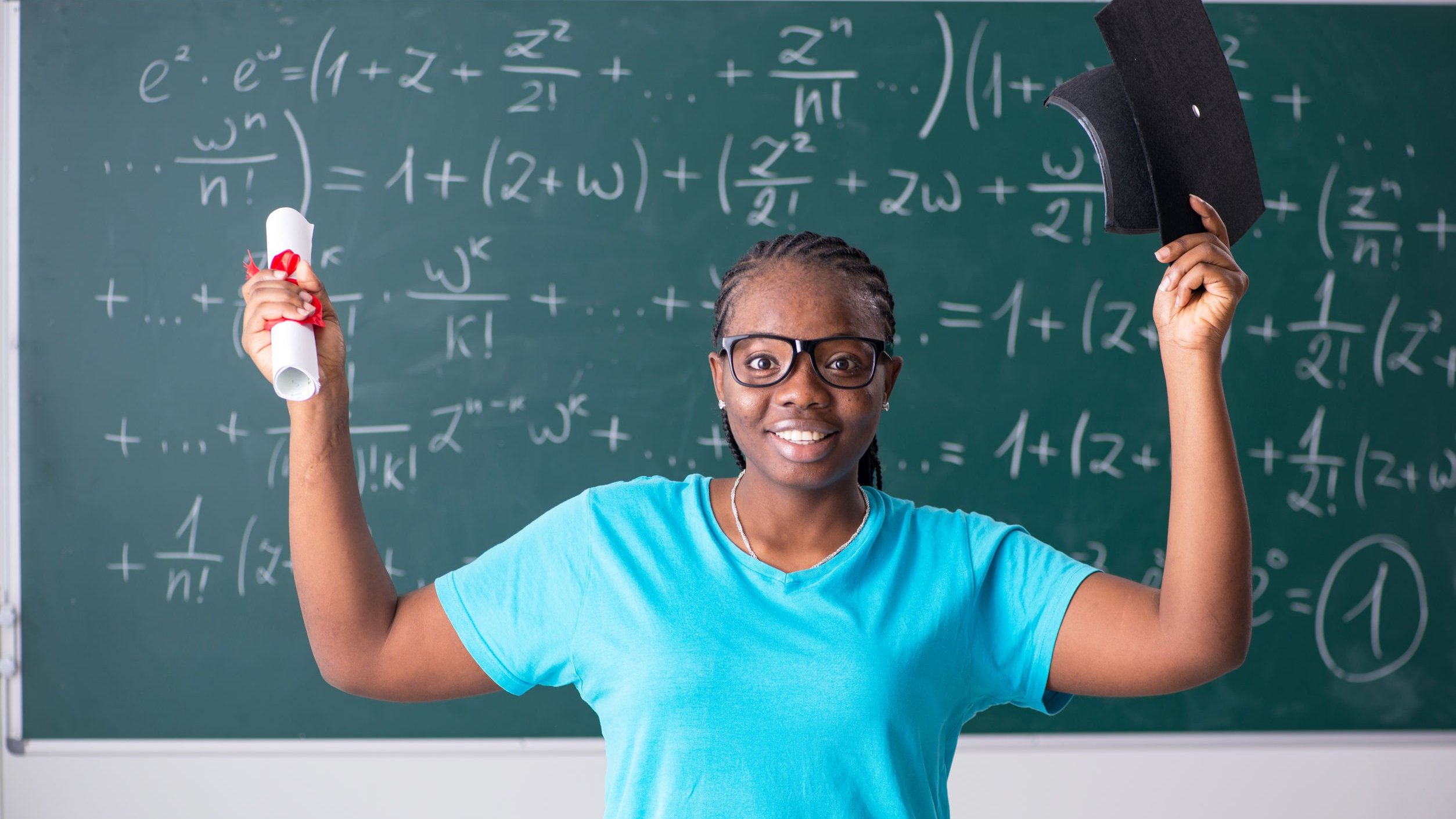 Mulher sorrindo, segurando diploma e capelo de formatura.