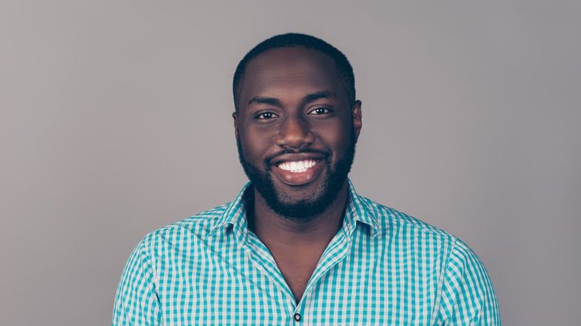 Homem de frente sorrindo com camisa xadrez