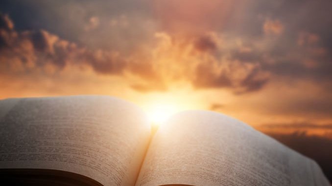 Bíblia aberta com o pôr do sol ao fundo