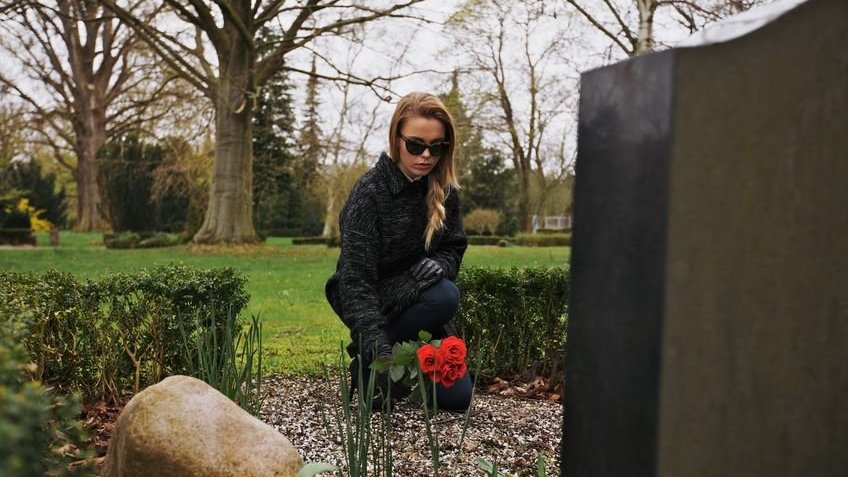 Mulher colocando flor em túmulo