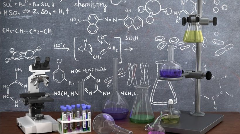 Tubos de ensaio de laboratório químico e objetos na mesa com um quadro escrito ao fundo