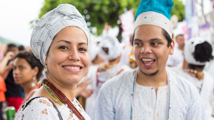 Homem e mulher com trajes da Umbanda sorrindo