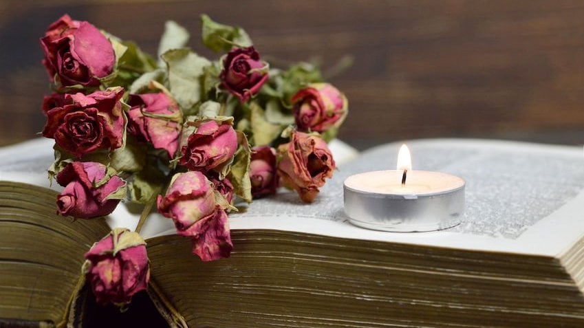 Uma vela e rosas secas em cima de uma bíblia