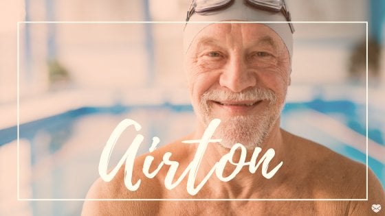 Homem de meia idade, em piscina, sorrindo, com o nome Airton escrito em branca.