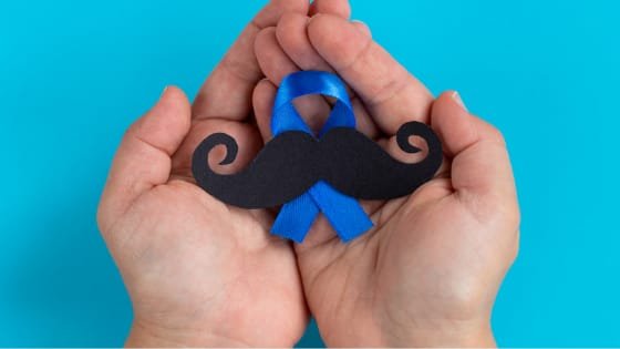Símbolo do Novembro Azul com um bigode em cima de uma mão com o fundo azul