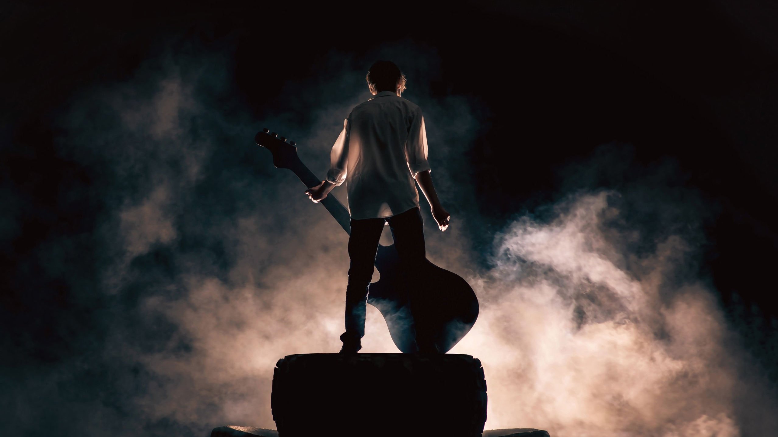 Yaroslav Urban / 123RF Homem segurando guitarra, rodeado de fumaça, em cima de palco de show