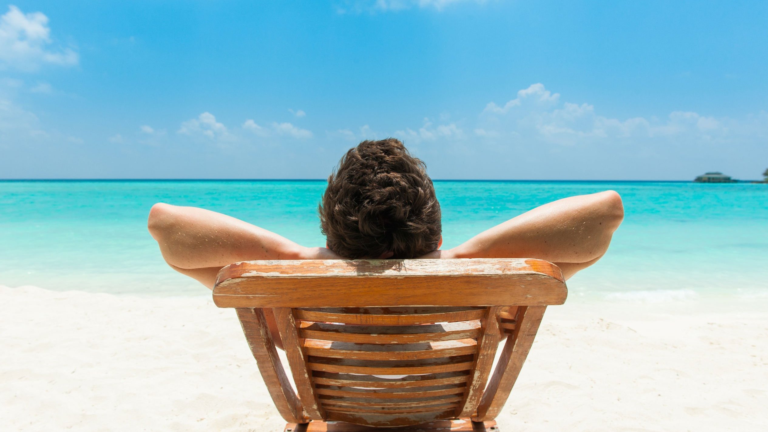 Homem sentado, descansando de frente para o mar.