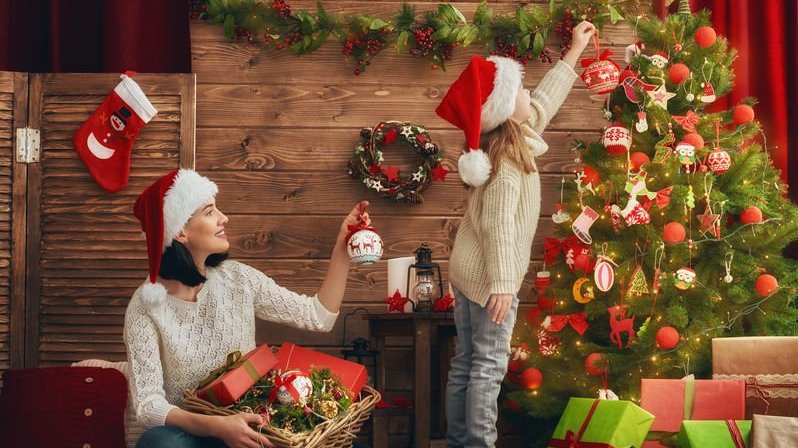 Mãe e filha decoram a árvore de Natal na sala.