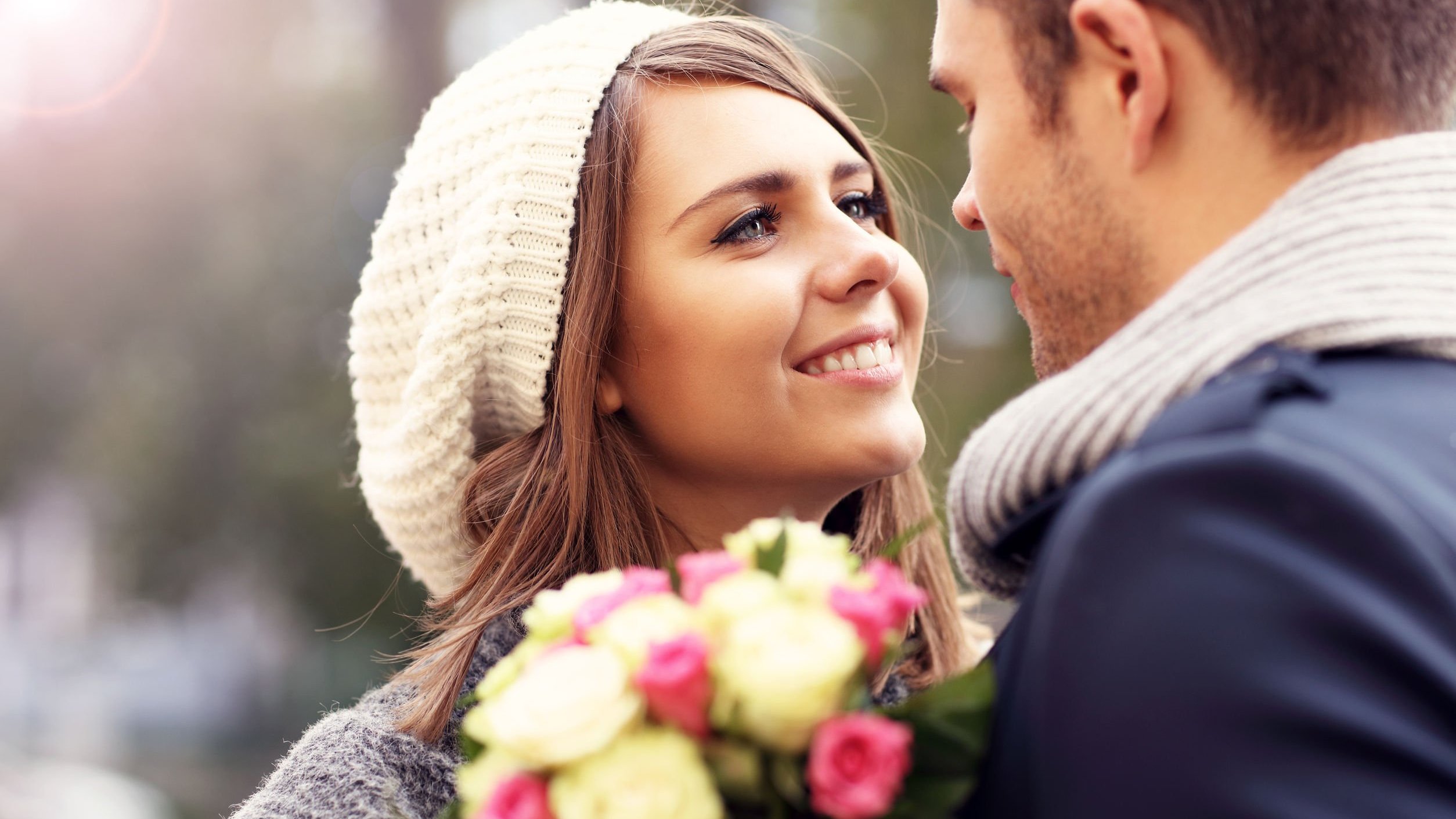 Mulher olhando para homem e sorrindo, segurando flores.