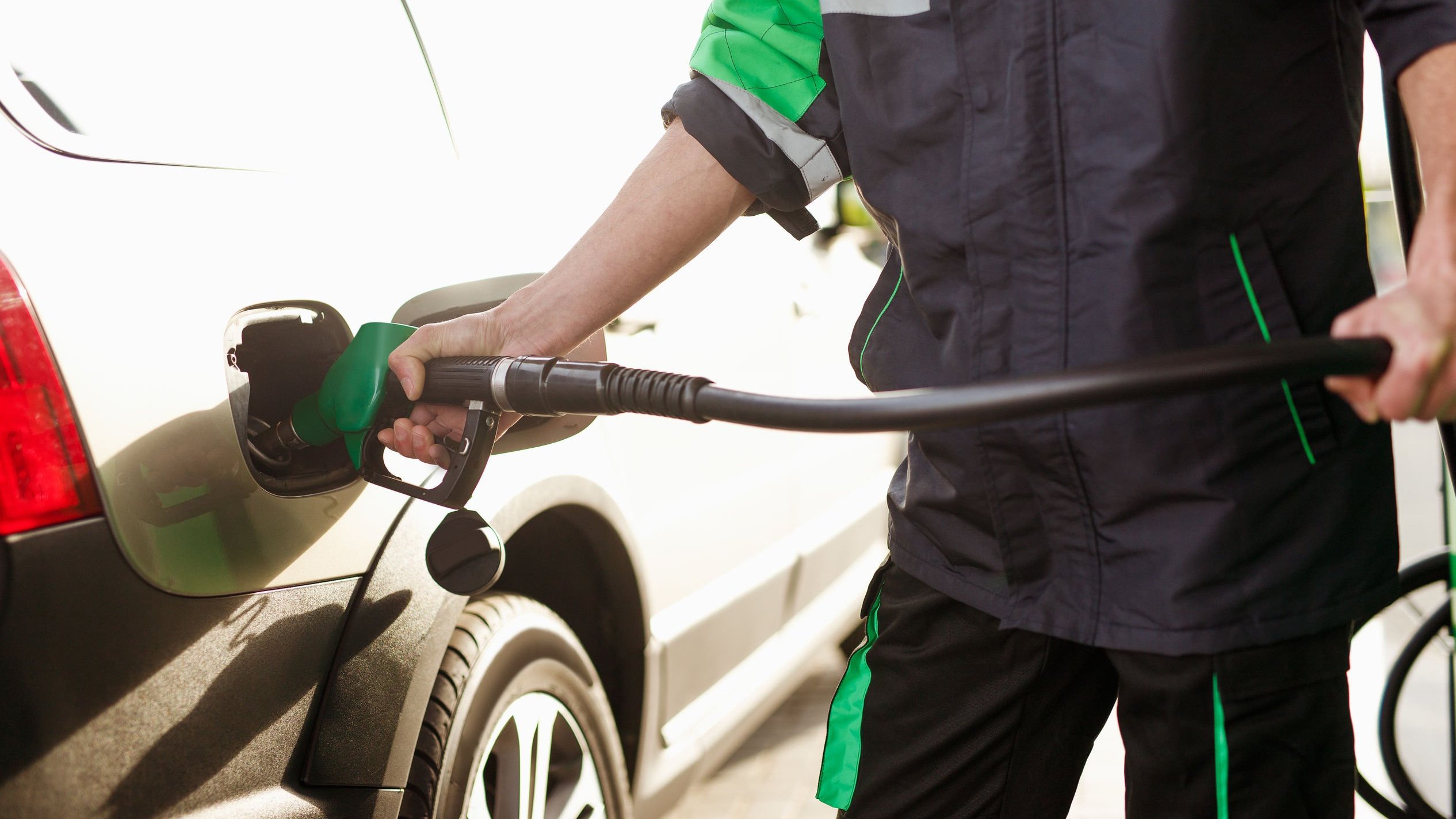 Frentista de posto de gasolina, colocando gasolina em carro.