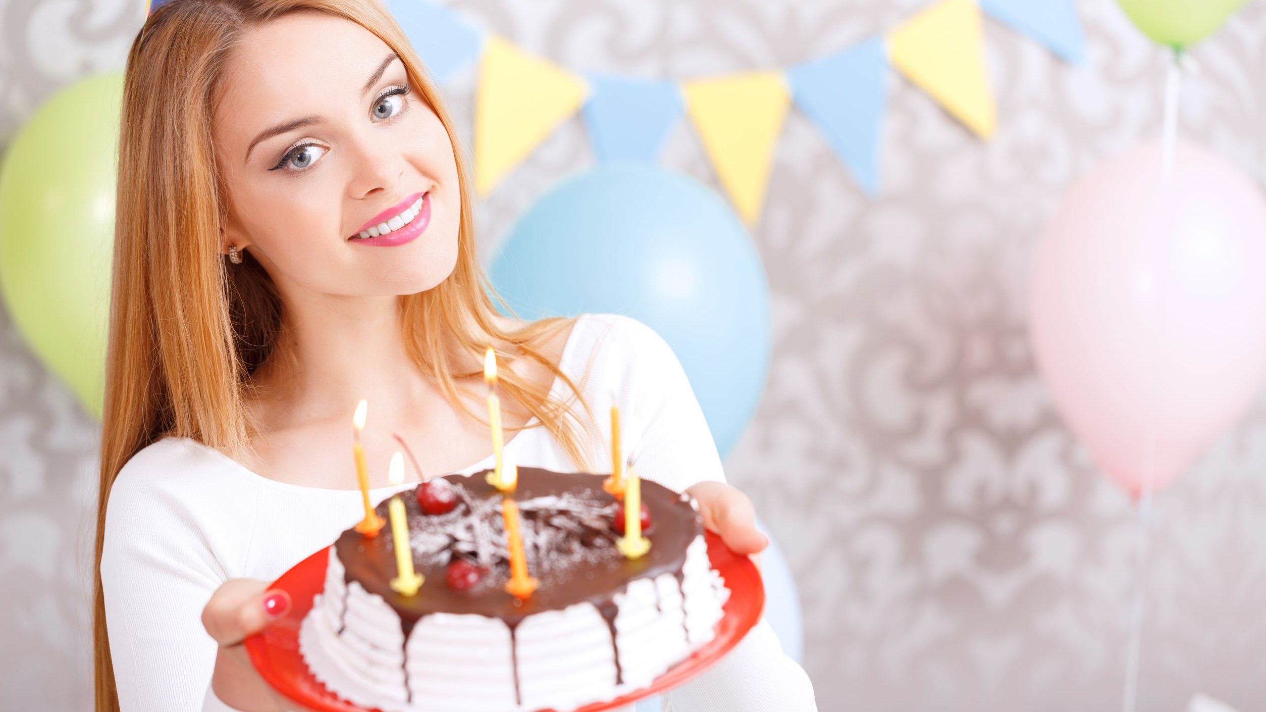Mulher sorrindo, segurando bolo de aniversário.