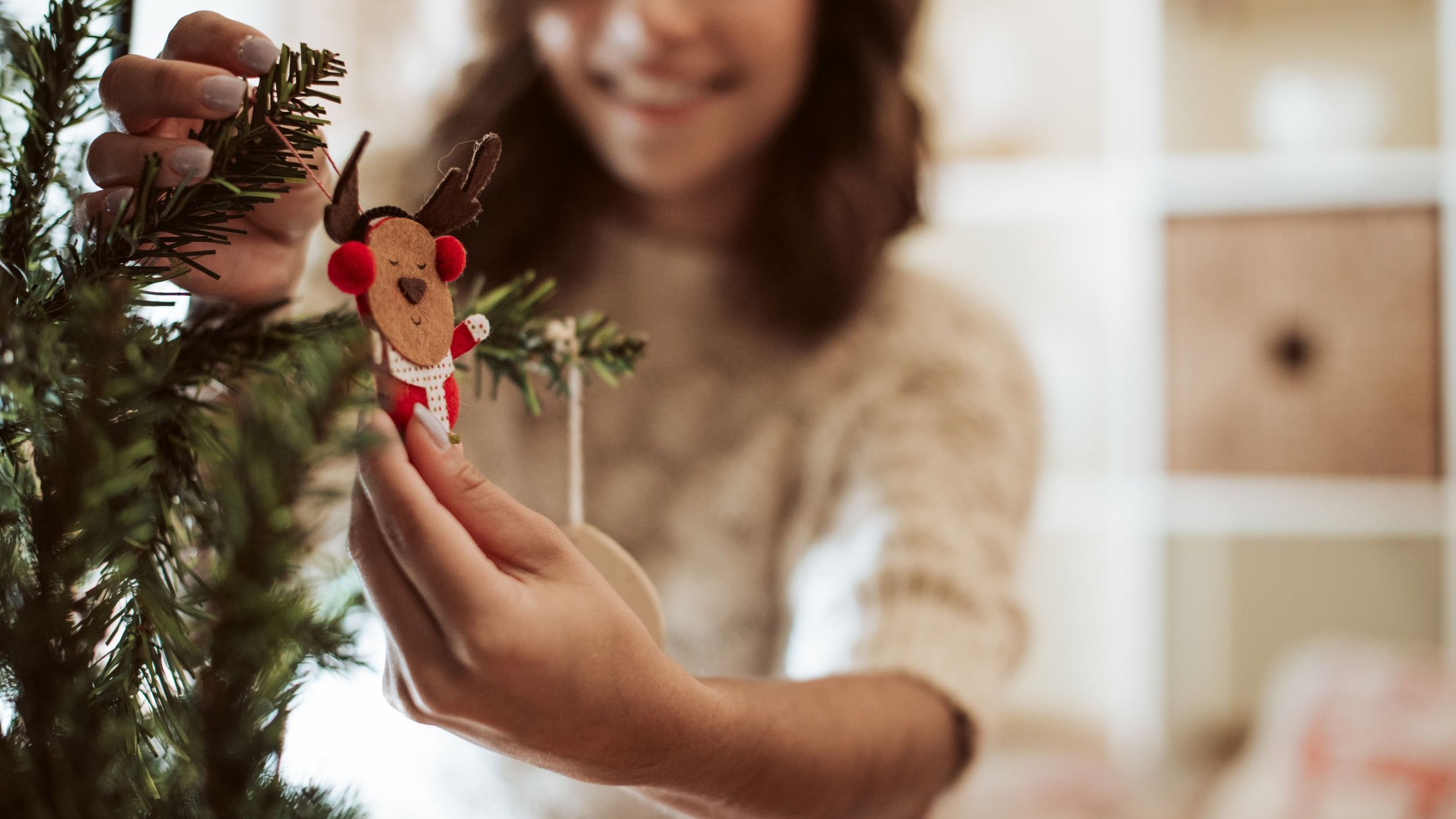 Mulher decorando árvore de Natal.