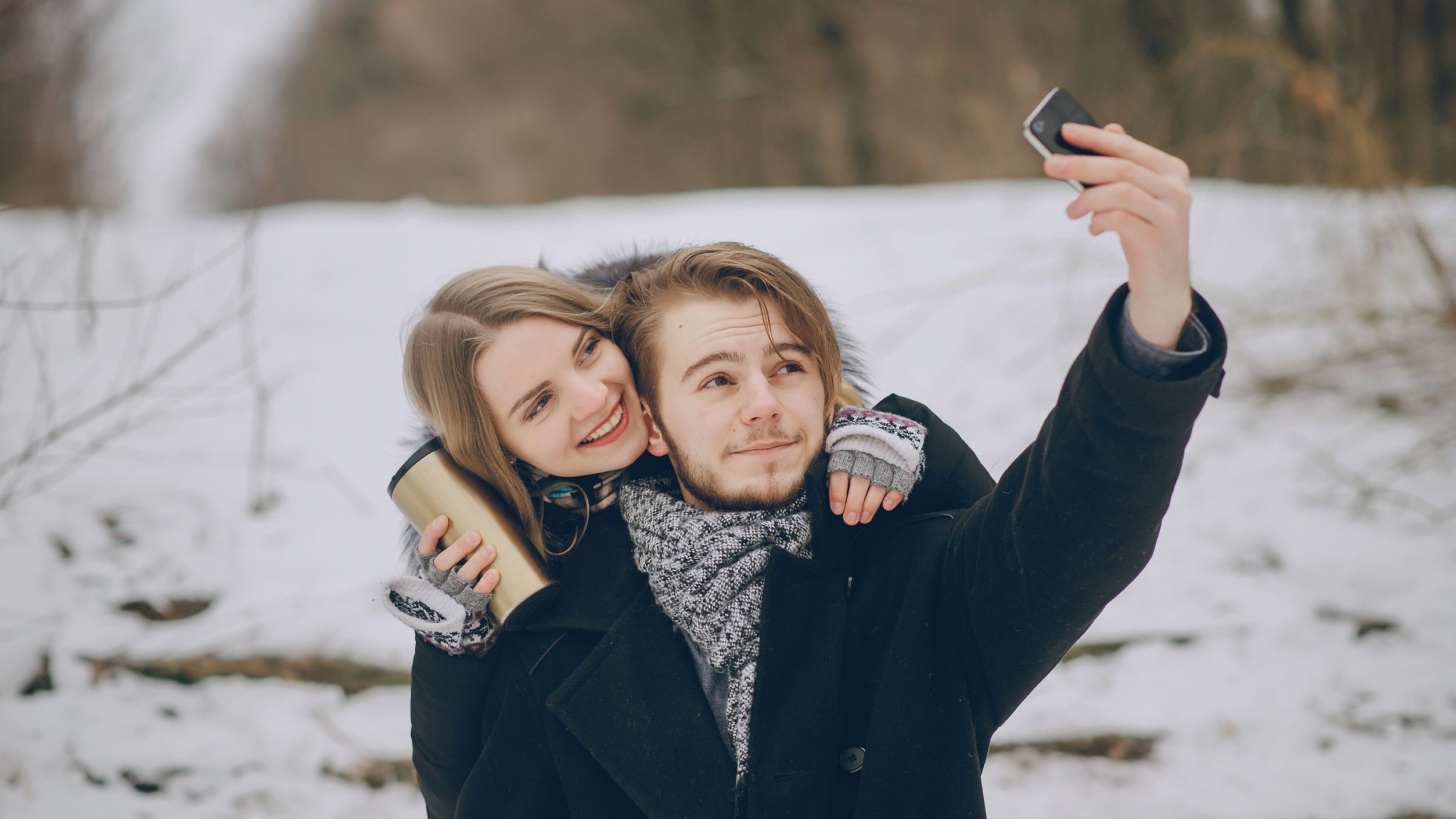 Casal tirando selfie em lugar com neve.