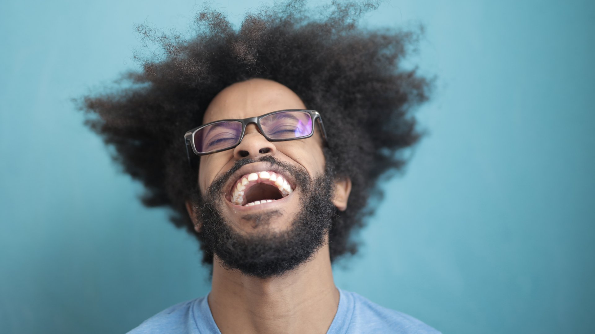 Homem negro usando óculos sorrindo largo