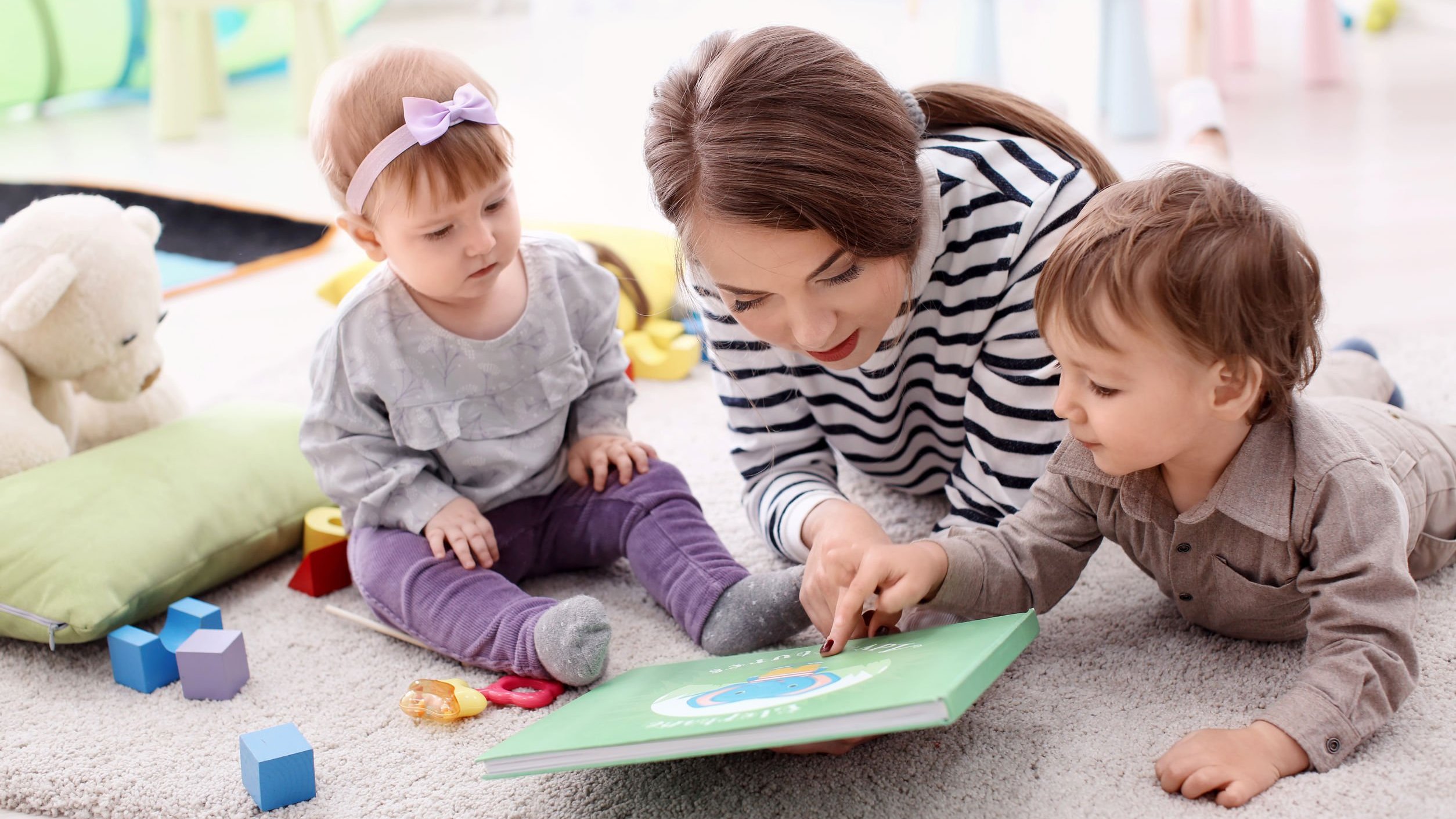 Mulher babá junto com crianças, vendo livro.