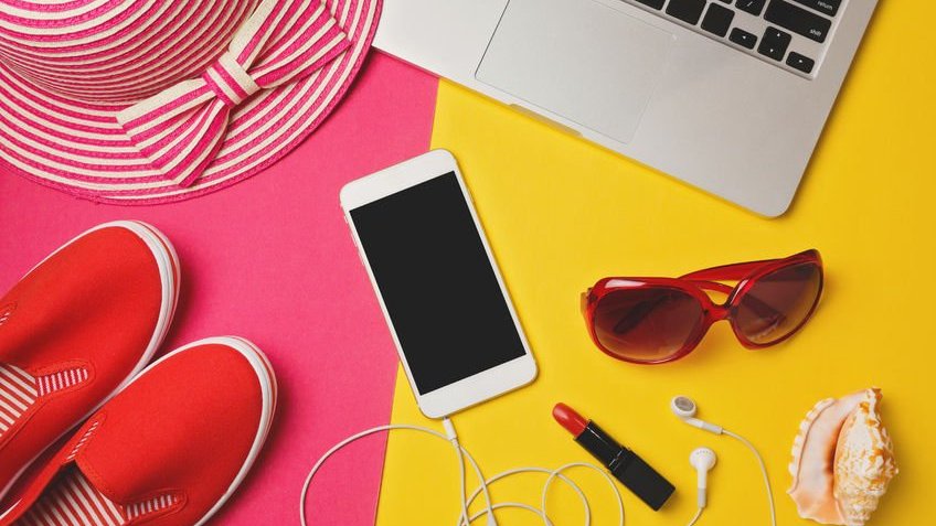 Conceito de verão com notebook, celular, fone de ouvido e objetos de praia sobre a mesa.