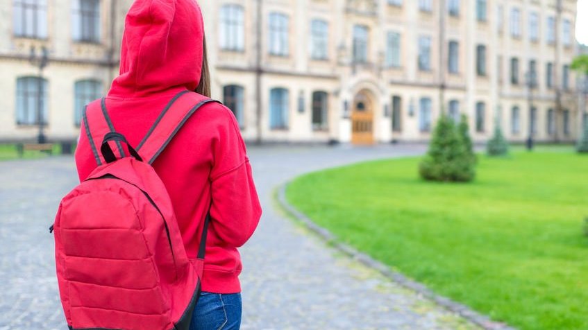 Pessoa com mochila nas costas entrando em faculdade