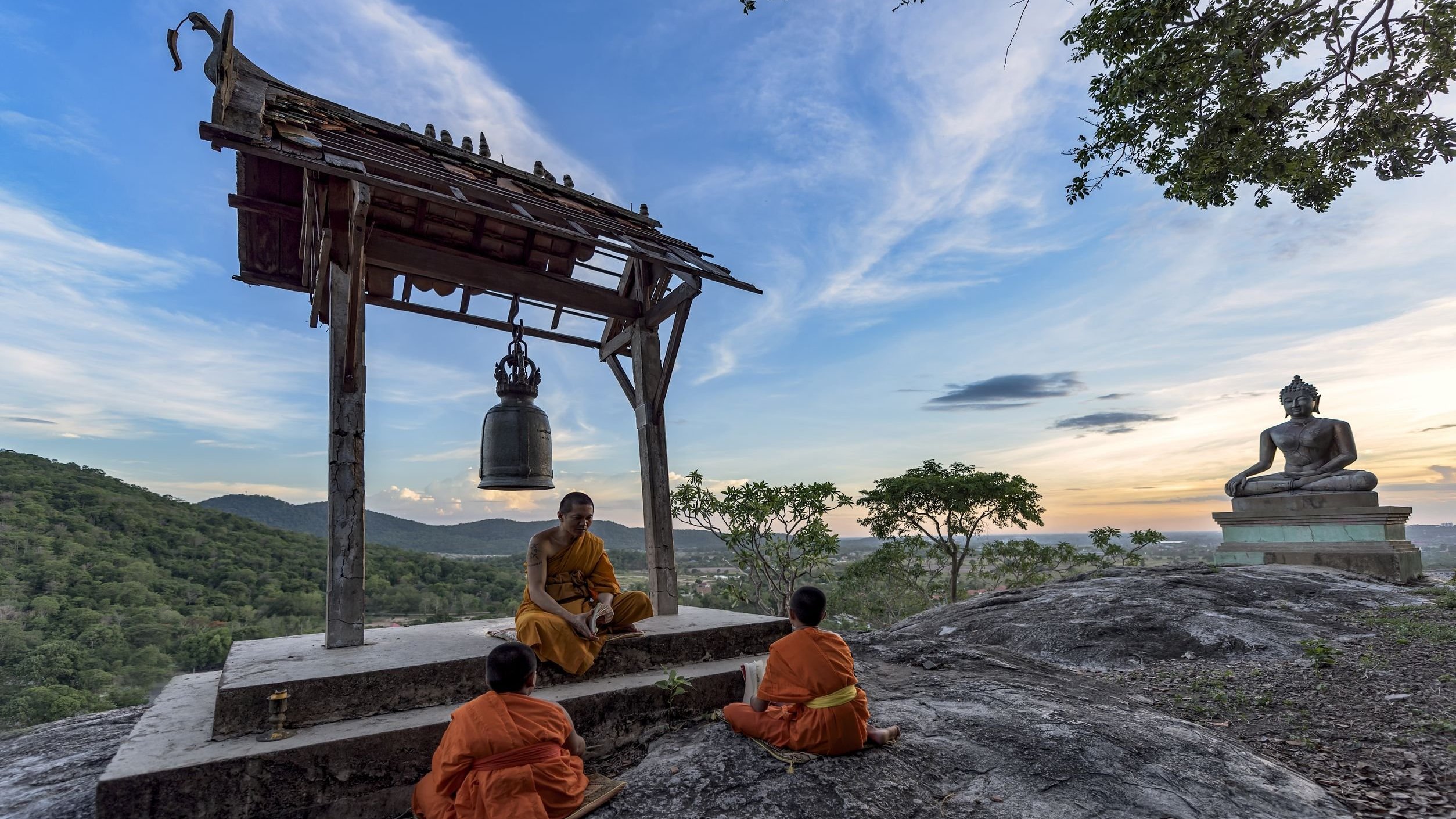 Homens monges meditando em topo de montanha.