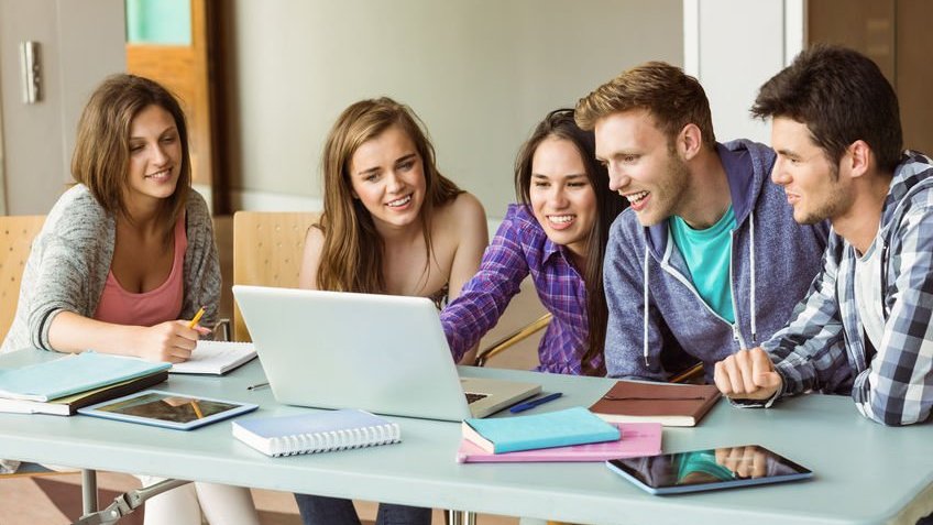 Amigos reunidos em mesa e notebook no meio