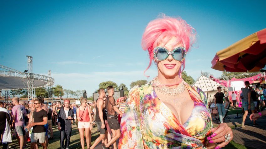Drag queen com cabelo rosa e óculos azuis