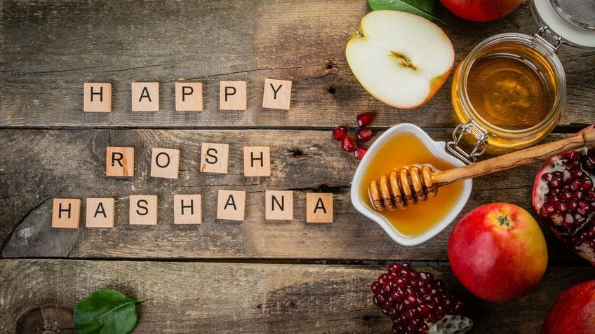 Letras formando Feliz Rosh Hashana e alimentos ao lado